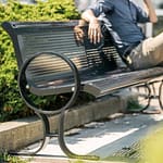 commercial outdoor metal park and memorial bench on the street with a man resting on it