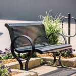 memorial black metal park bench on the street surrounded by purple flowers